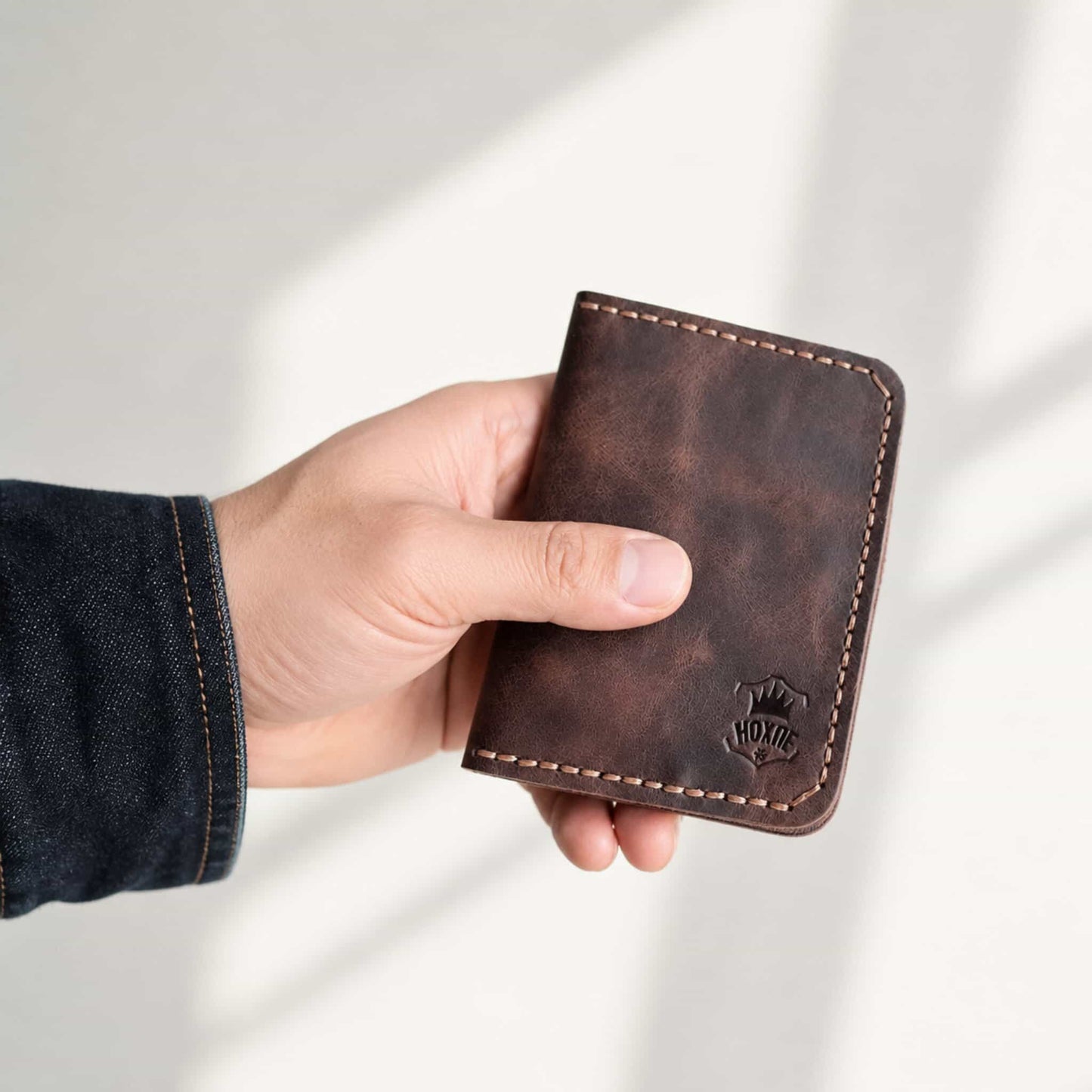 Hand holding handmade dark brown leather bifold card wallet — Hoxne Leather
