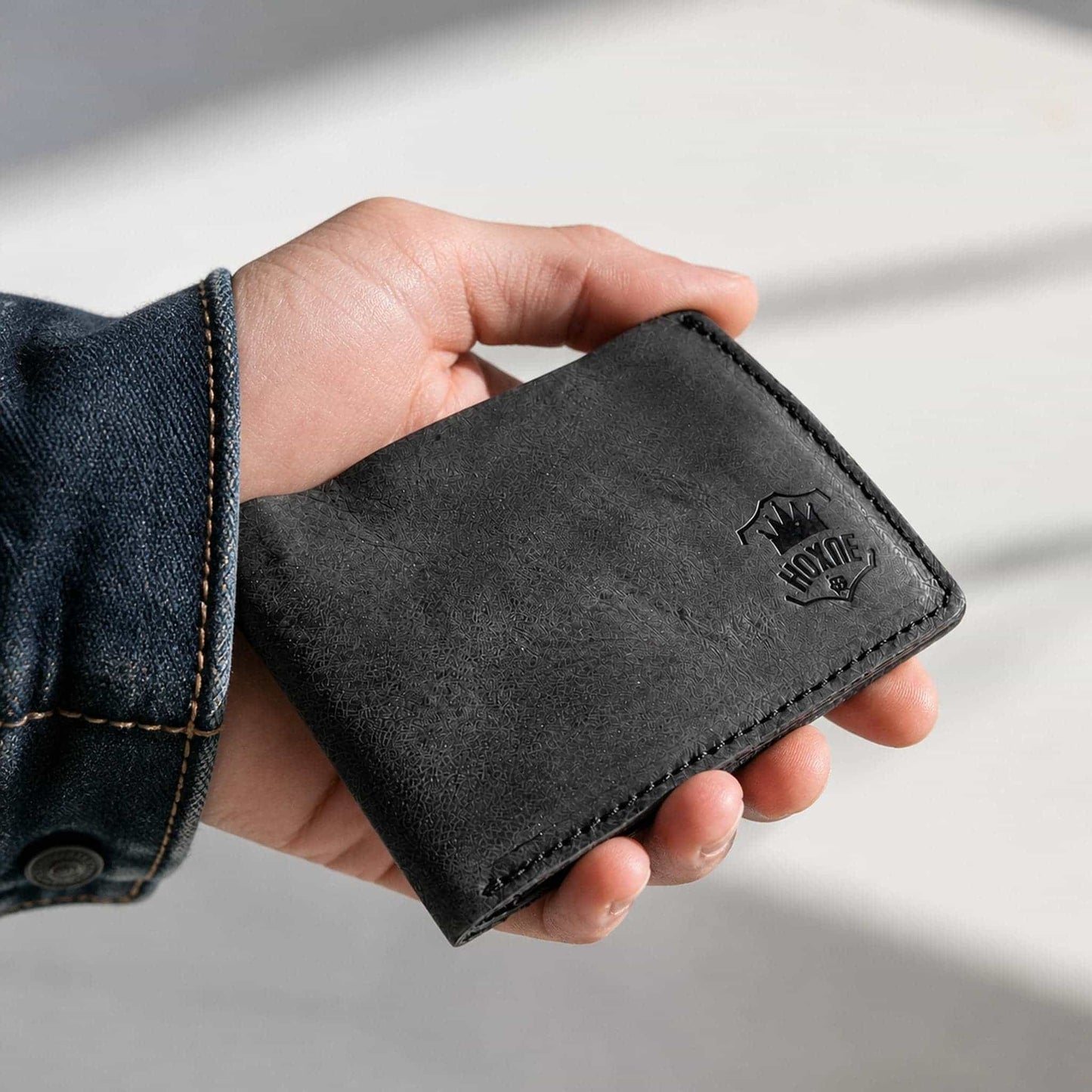 Hand holding Hoxne Leather bifold wallet, full-grain leather