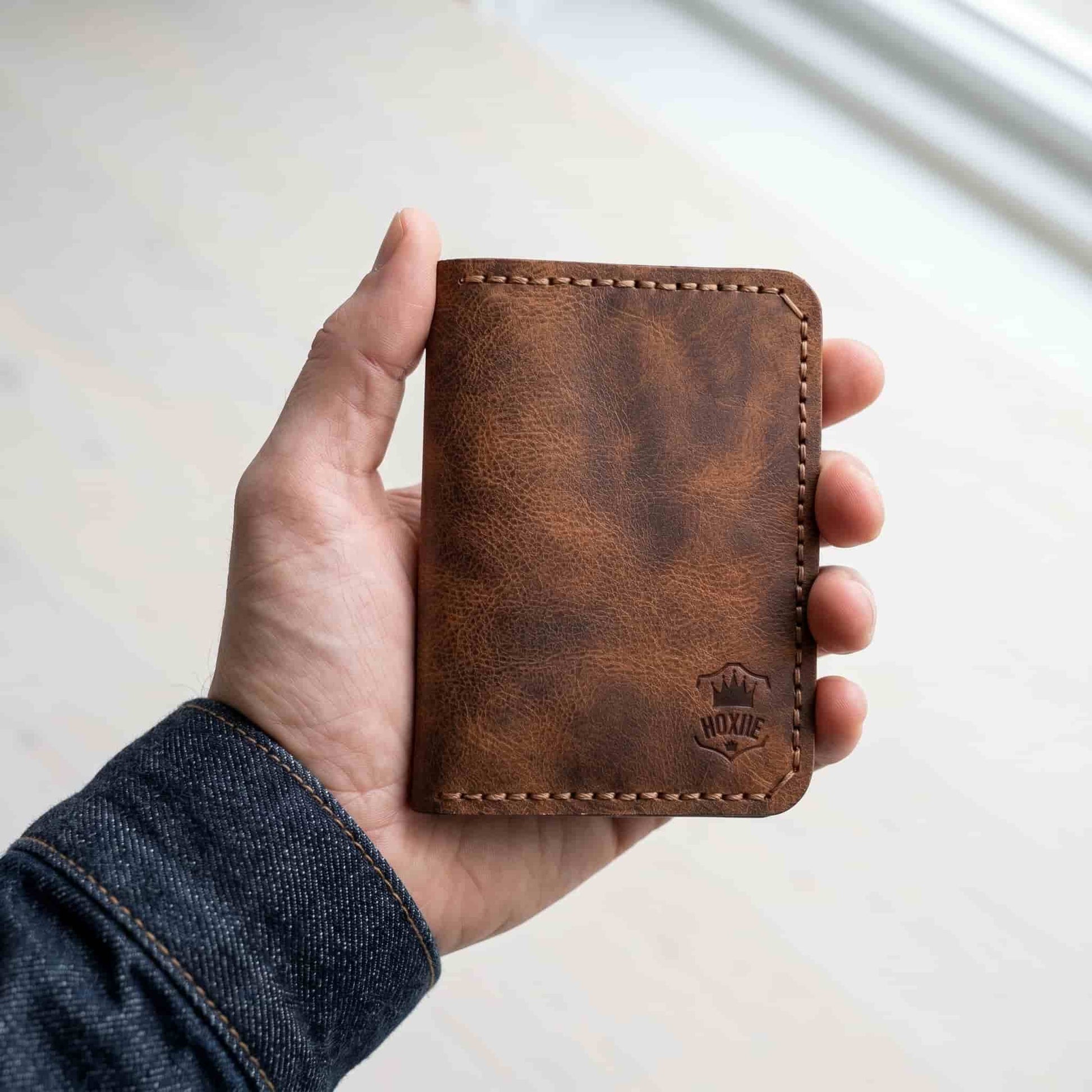 Hand holding Hoxne Leather passport holder, full-grain leather
