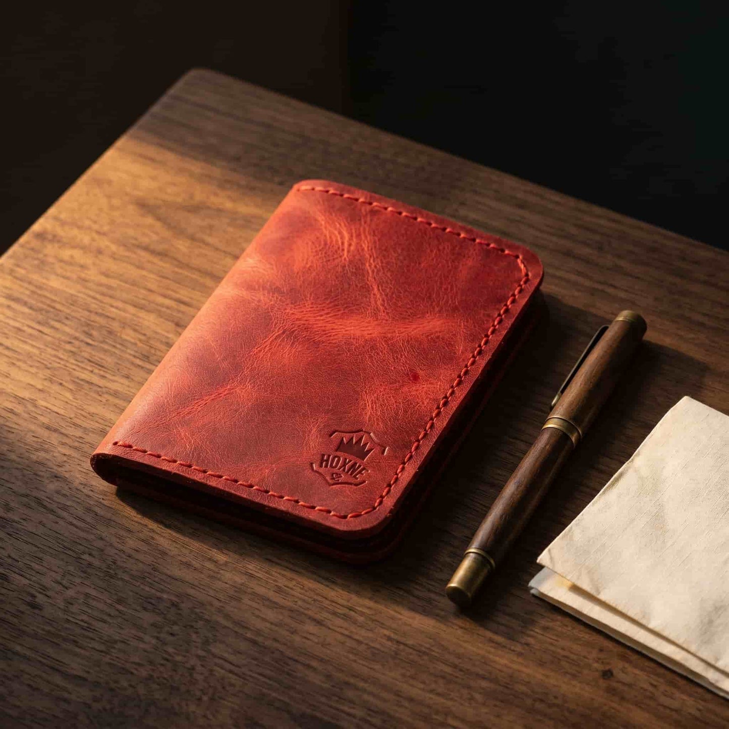 Hoxne Leather passport holder in red, lifestyle desk photo