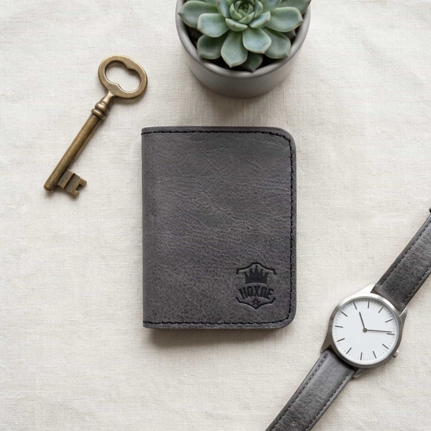 Dark brown leather bifold card wallet with key and watch lifestyle flat lay — Hoxne Leather